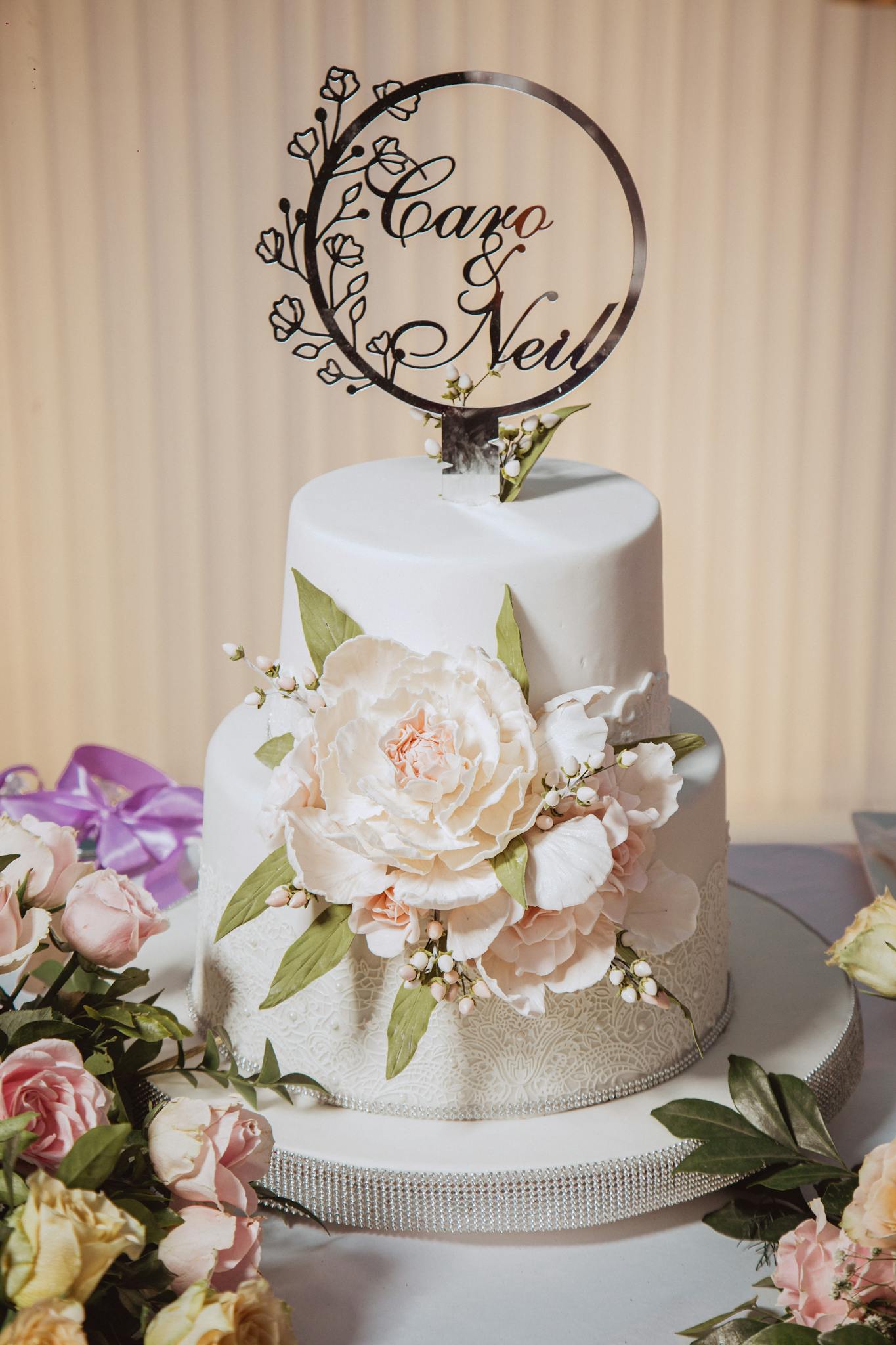 Beautifully decorated wedding cake with floral accents and personalized topper for a special occasion.